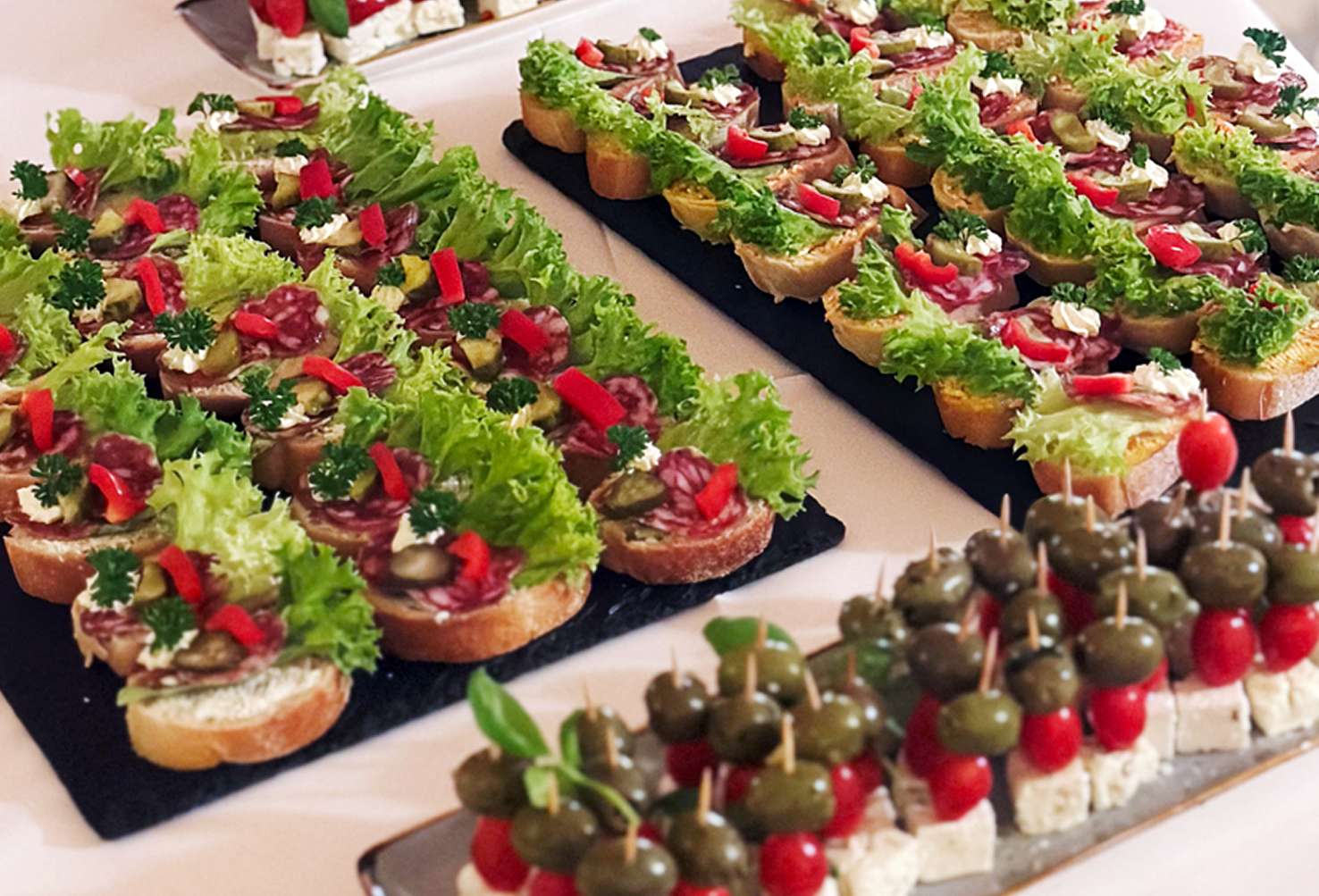 Belegte Brothäppchen und Spieße mit Käse, Tomaten und Oliven auf einem Buffet