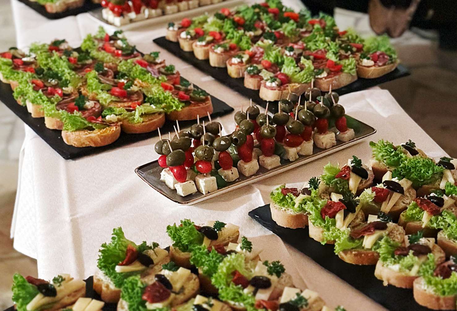 Cateringbuffet mit belegten Brothäppchen und Antipastispießen auf mehreren Platten