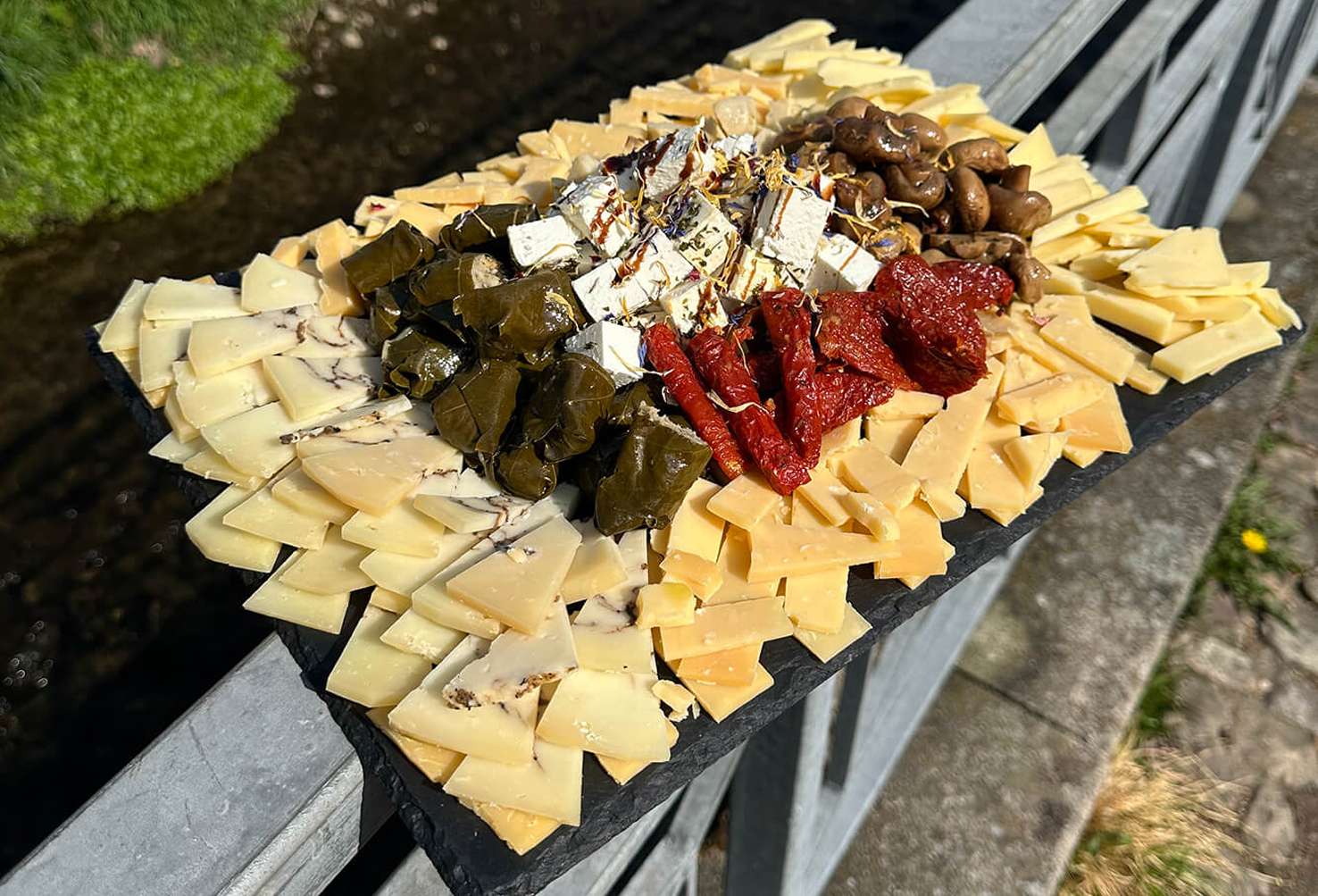 Käseplatte mit gefüllten Weinblättern, Champignons, getrockneten Tomaten und mariniertem Käse