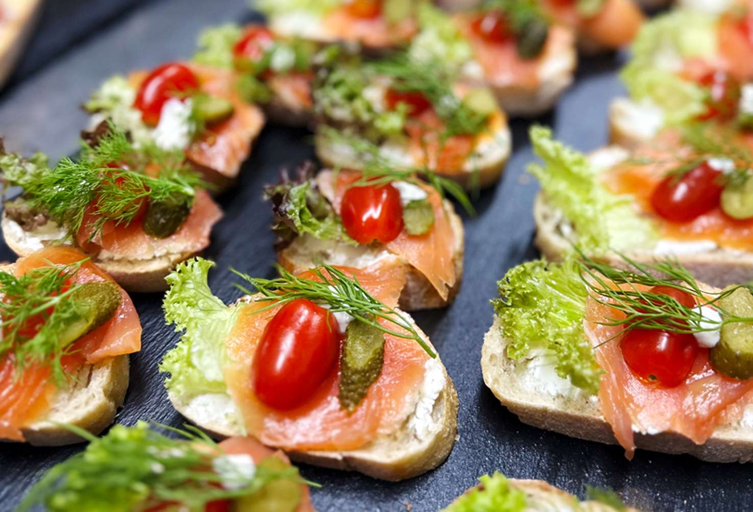 Lachshäppchen mit Tomaten, Dill und Kapern auf kleinen Brotscheiben