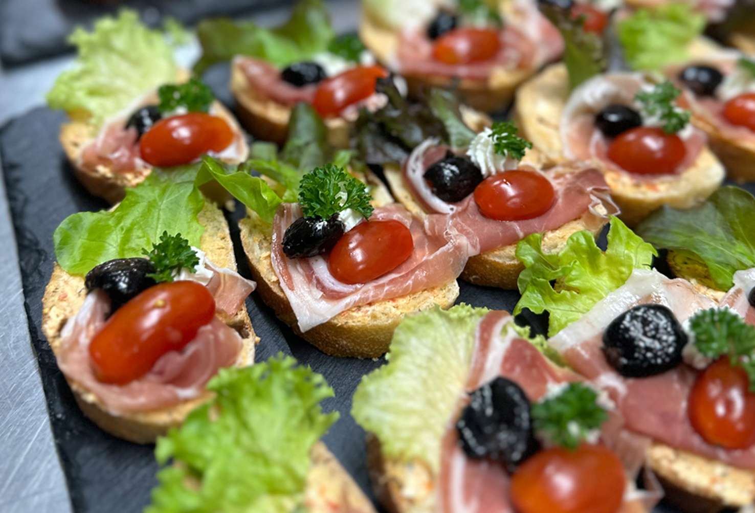 Schinkenhäppchen mit Tomaten, dunklen Oliven und Salat