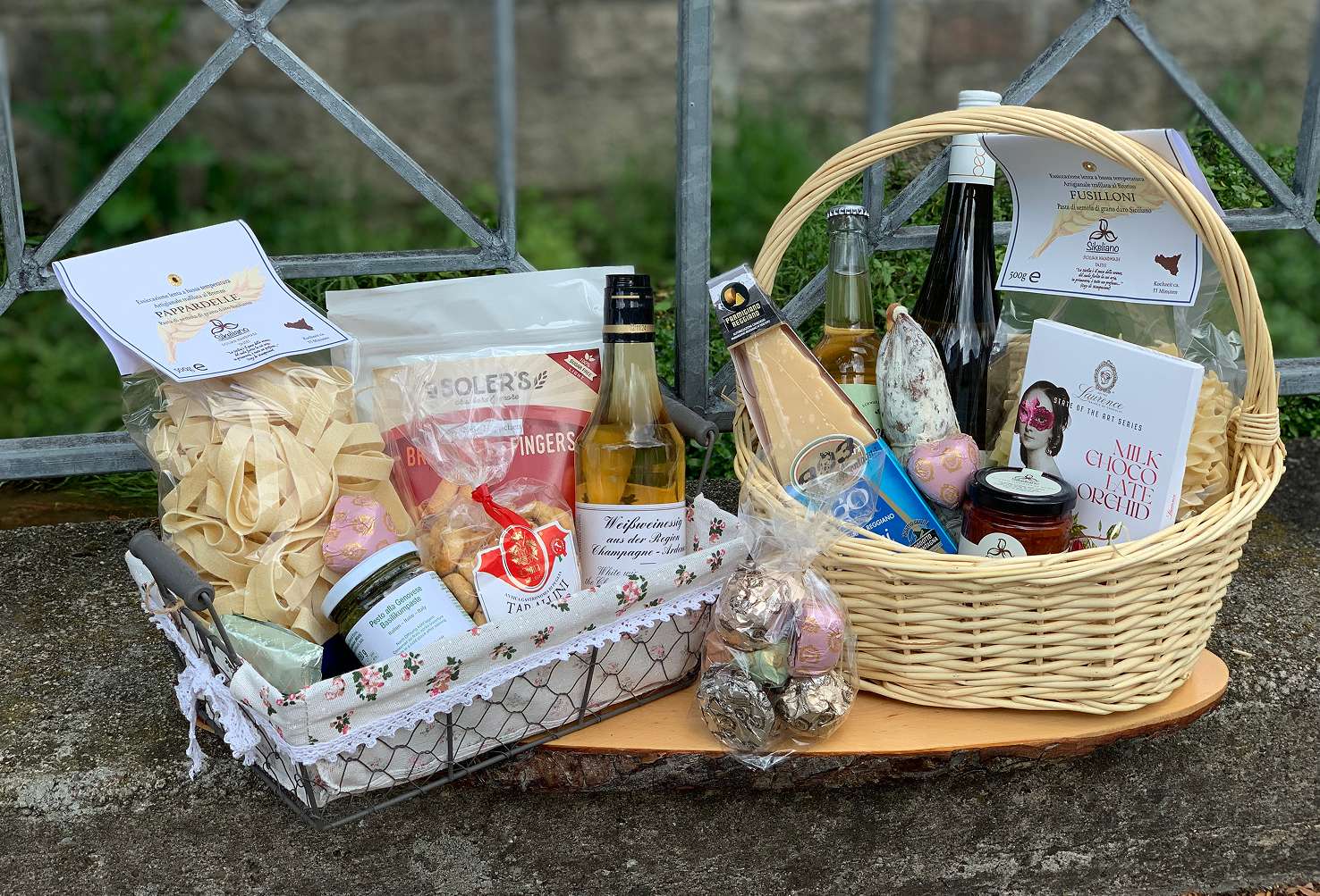 Zwei unterschiedlich zusammengestellte Feinkost-Geschenkkörbe mit Pasta, Flaschen und Gläsern